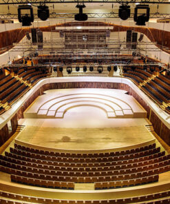 La sala concerti, progettata con la Serie Hyperion per Teatri e Studi TV, è dotata di posti a sedere a gradoni e di un ampio palco centrale completato da impianti di illuminazione dall'alto. I posti a sedere sono configurati in una disposizione semicircolare, che mette in mostra accenti in legno ed elementi di design moderno in tutto l'interno.