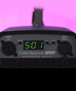 Primo piano di un dispositivo ColorSource Spot con display digitale che mostra 5:01. Ha connessioni DMX etichettate In e Thru. Lo sfondo è rosa acceso.